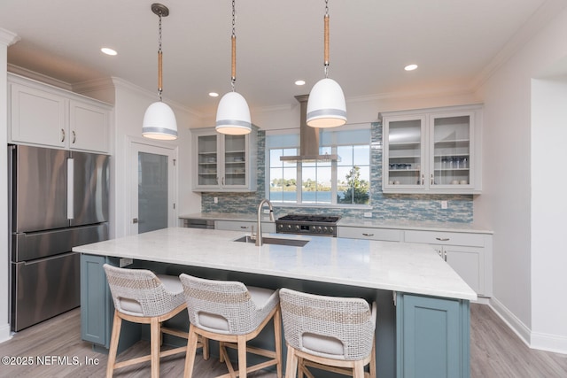 kitchen featuring hanging light fixtures, a kitchen island with sink, sink, and stainless steel fridge