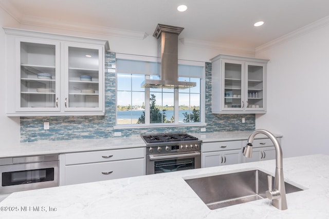 kitchen with appliances with stainless steel finishes, tasteful backsplash, sink, island exhaust hood, and light stone countertops