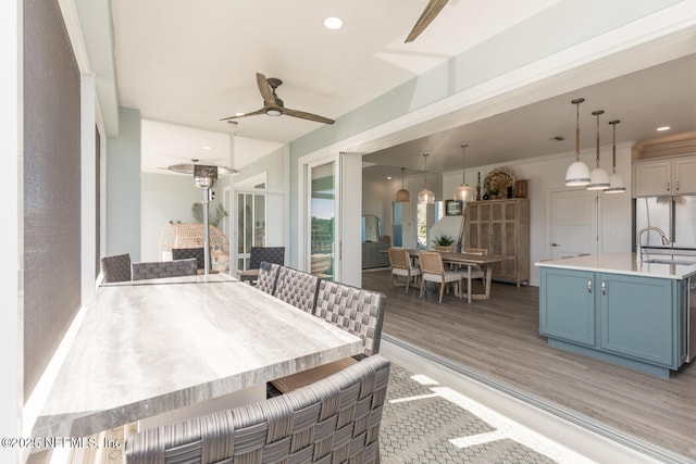 dining area with ceiling fan, sink, a fireplace, and light hardwood / wood-style flooring