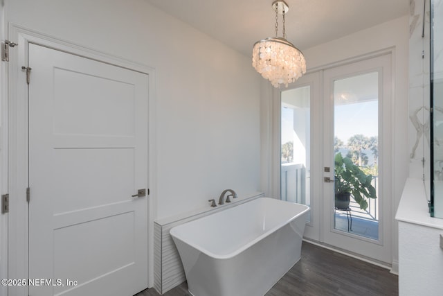 bathroom with an inviting chandelier, a bath, and hardwood / wood-style flooring