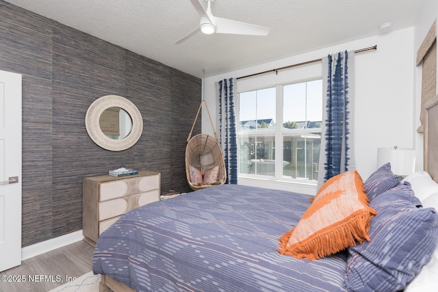 bedroom with hardwood / wood-style floors, a textured ceiling, and ceiling fan