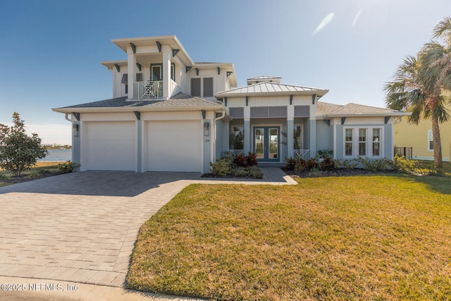 view of front facade with a garage, a front lawn, french doors, and a balcony