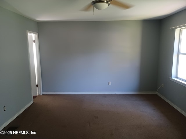 spare room with dark carpet and ceiling fan