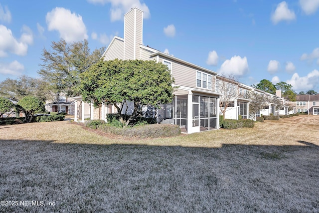 back of house featuring a sunroom and a lawn