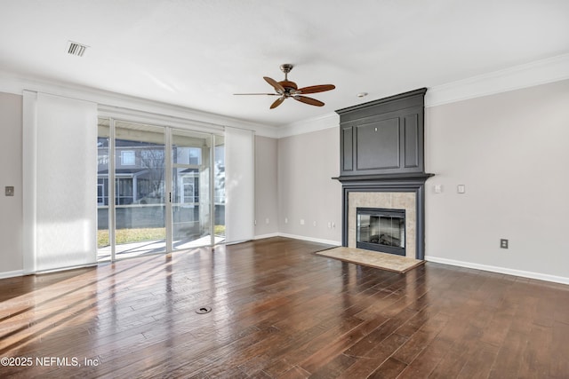 unfurnished living room featuring a tiled fireplace, ornamental molding, dark hardwood / wood-style floors, and ceiling fan