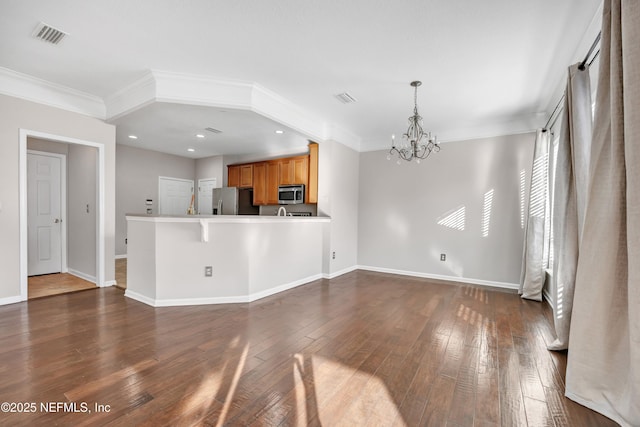 kitchen with hanging light fixtures, appliances with stainless steel finishes, dark wood-type flooring, and kitchen peninsula