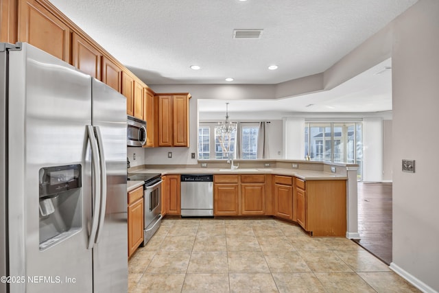 kitchen with appliances with stainless steel finishes, pendant lighting, sink, light tile patterned floors, and kitchen peninsula