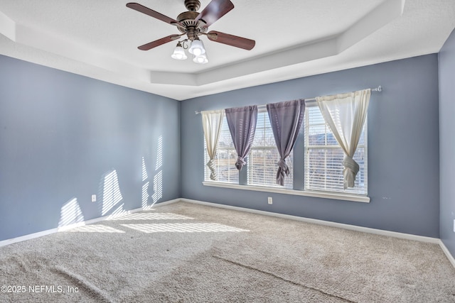 empty room featuring carpet floors, ceiling fan, and a tray ceiling