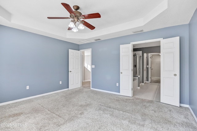 unfurnished bedroom featuring a raised ceiling, light colored carpet, and ceiling fan