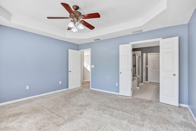 unfurnished bedroom featuring light carpet, ceiling fan, and a tray ceiling