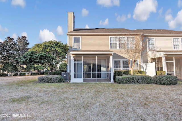 back of property with cooling unit, a sunroom, and a lawn