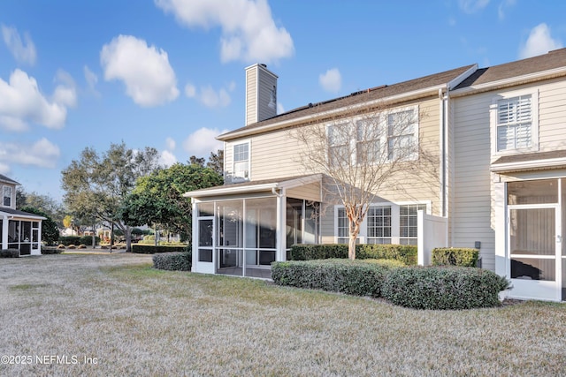 rear view of property with a lawn and a sunroom