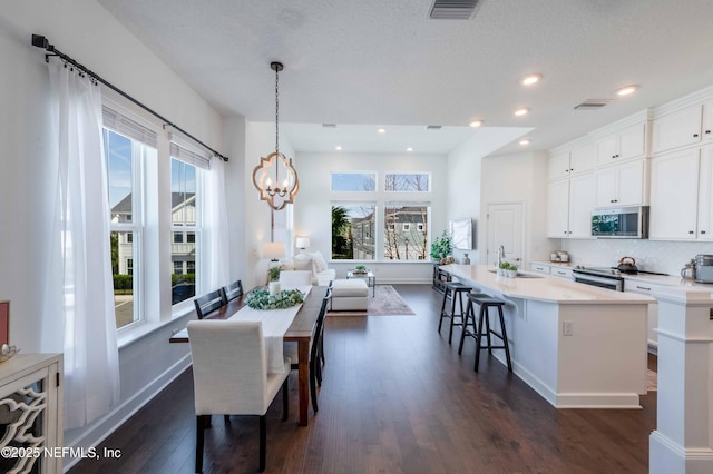 dining area featuring dark hardwood / wood-style floors, sink, and an inviting chandelier