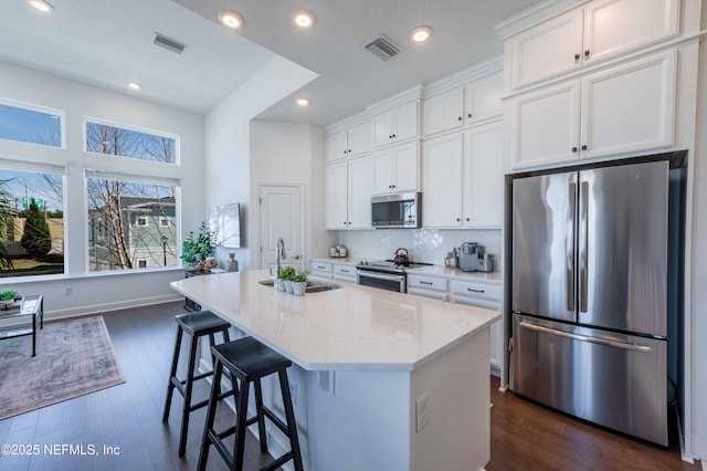 kitchen featuring stainless steel appliances, a kitchen island with sink, sink, and white cabinets