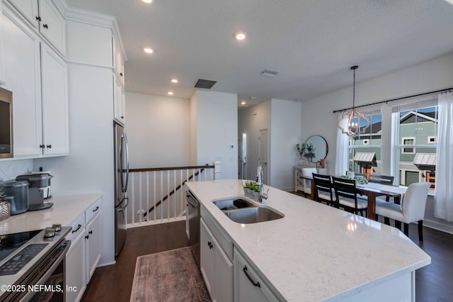 kitchen with sink, white cabinetry, hanging light fixtures, stainless steel appliances, and a center island with sink