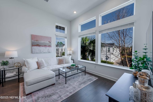 living room featuring a towering ceiling and dark wood-type flooring