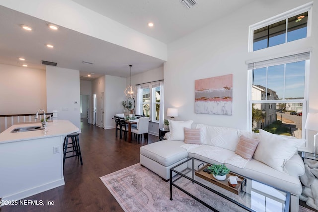 living room featuring sink, dark wood-type flooring, and a chandelier