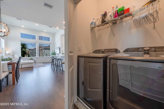 laundry room with a notable chandelier, washing machine and dryer, and dark hardwood / wood-style floors