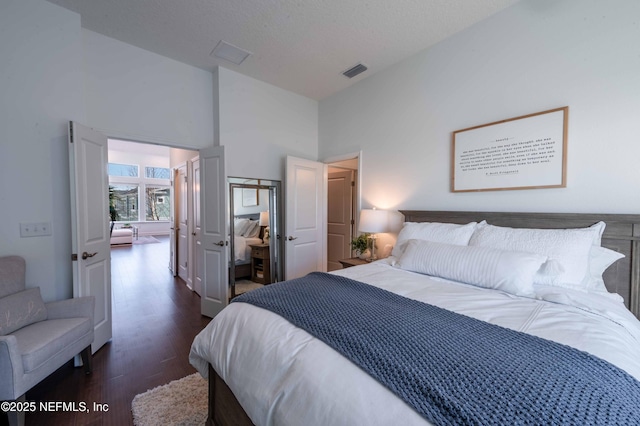 bedroom featuring dark hardwood / wood-style flooring, high vaulted ceiling, and a textured ceiling