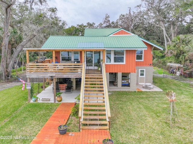 rear view of house with a deck, a patio, and a lawn