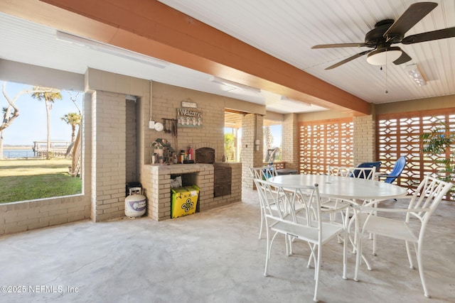 dining space with ceiling fan, brick wall, and plenty of natural light