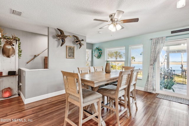 dining area featuring ceiling fan, hardwood / wood-style flooring, a textured ceiling, and a water view