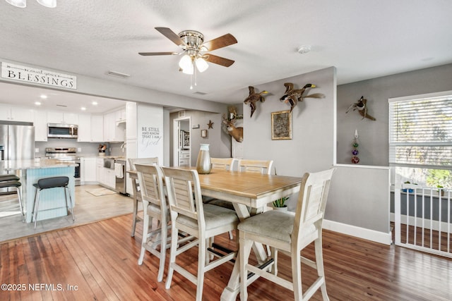 dining room featuring ceiling fan, a textured ceiling, and light hardwood / wood-style floors