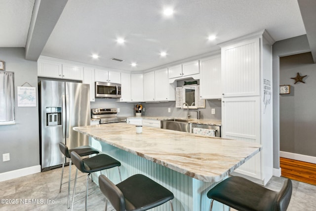 kitchen featuring white cabinetry, appliances with stainless steel finishes, sink, and a center island