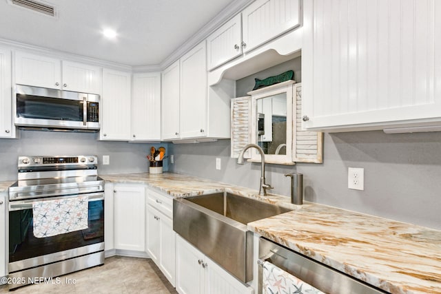 kitchen featuring white cabinetry, appliances with stainless steel finishes, light stone countertops, and sink