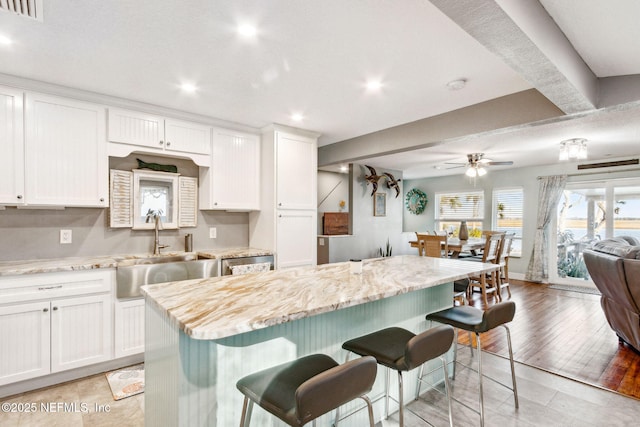 kitchen featuring sink, a kitchen breakfast bar, white cabinets, and a kitchen island