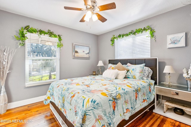 bedroom with multiple windows, wood-type flooring, and ceiling fan