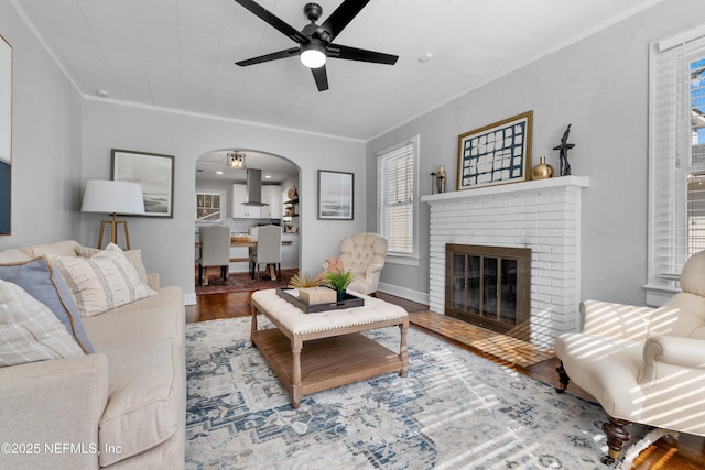 living room featuring crown molding, hardwood / wood-style flooring, a fireplace, and ceiling fan