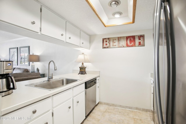 kitchen featuring a raised ceiling, white cabinetry, appliances with stainless steel finishes, and sink