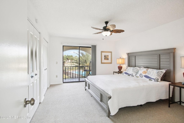 carpeted bedroom with ceiling fan, access to exterior, a textured ceiling, and two closets