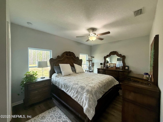 bedroom featuring dark wood-style floors, ceiling fan, a textured ceiling, and visible vents