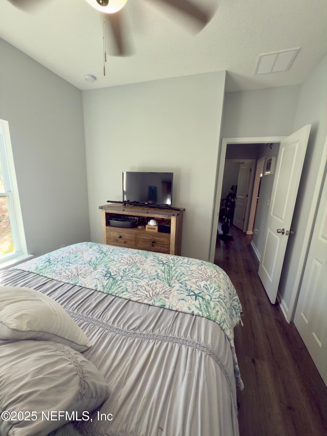 bedroom featuring dark wood-style floors, ceiling fan, visible vents, and baseboards