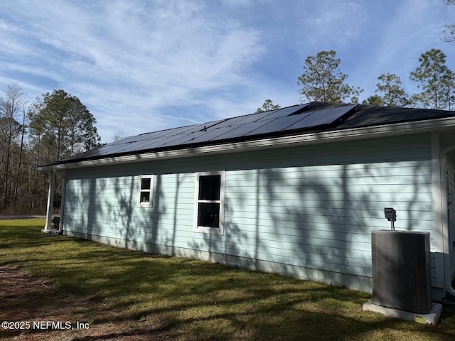 view of home's exterior with solar panels, central AC, and a yard