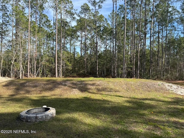 view of yard featuring a fire pit and a forest view