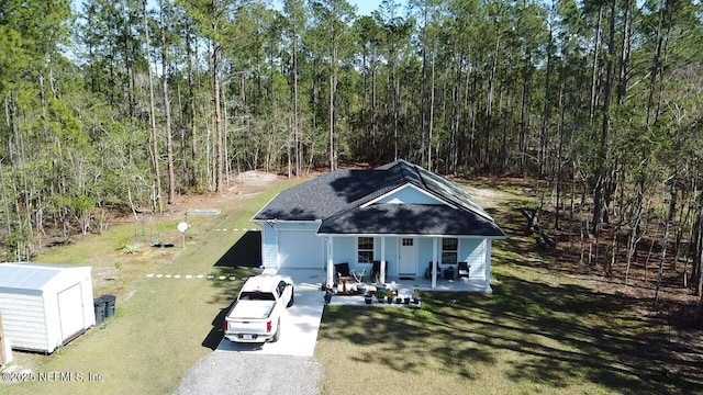 view of front of house featuring a porch, a front yard, and a view of trees