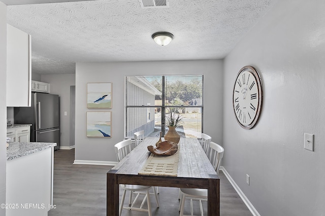 dining room featuring dark wood-type flooring and a textured ceiling