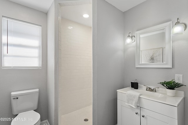 bathroom with vanity, toilet, and a tile shower