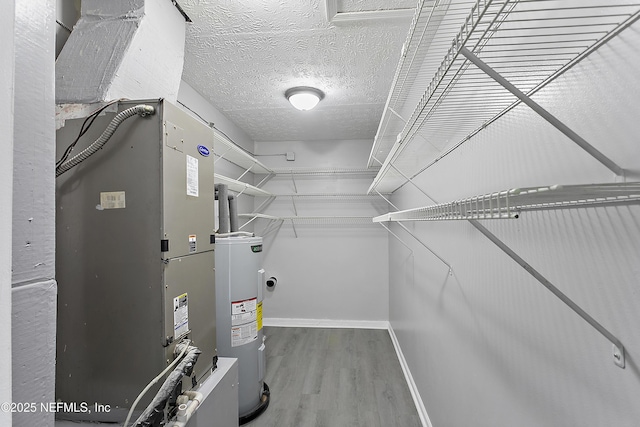 walk in closet with wood-type flooring and water heater