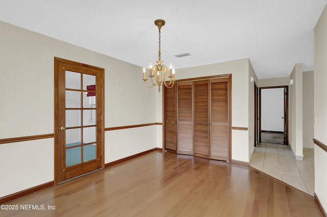 unfurnished dining area with a chandelier and light hardwood / wood-style floors