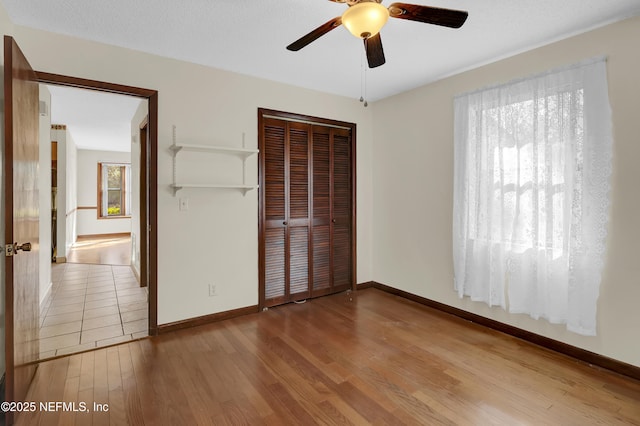 unfurnished bedroom featuring hardwood / wood-style flooring, ceiling fan, and a closet