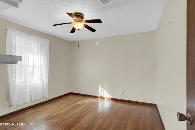 empty room featuring ceiling fan, hardwood / wood-style flooring, and a textured ceiling