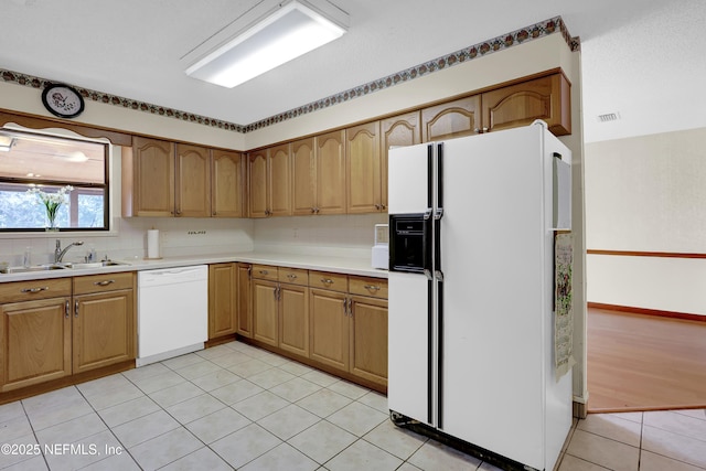 kitchen with light tile patterned flooring, white appliances, sink, and decorative backsplash