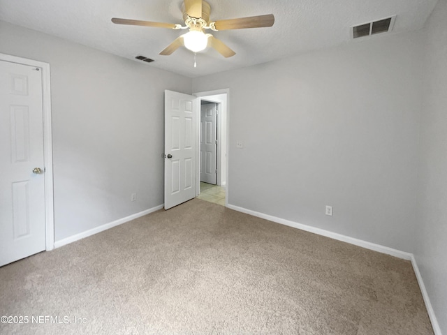 unfurnished room with ceiling fan, light carpet, and a textured ceiling