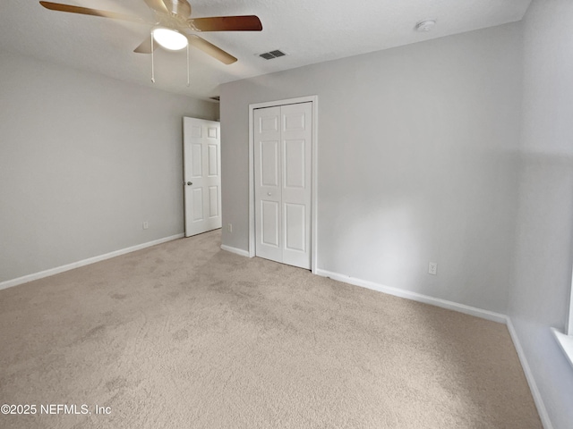 unfurnished bedroom with ceiling fan, light carpet, and a closet