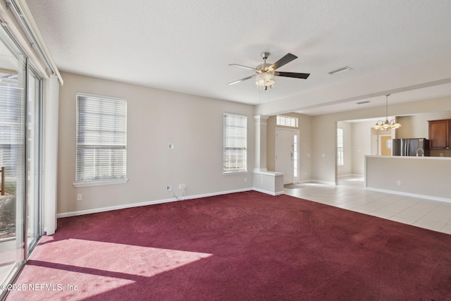 unfurnished living room with a healthy amount of sunlight, a textured ceiling, light carpet, and ornate columns