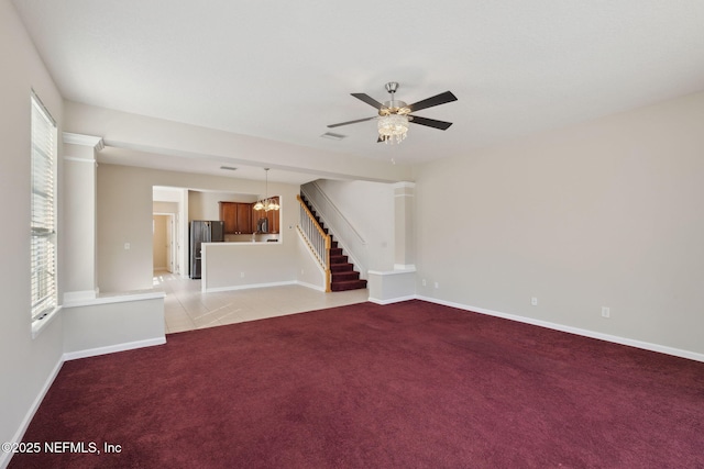 unfurnished living room with light carpet and ceiling fan with notable chandelier